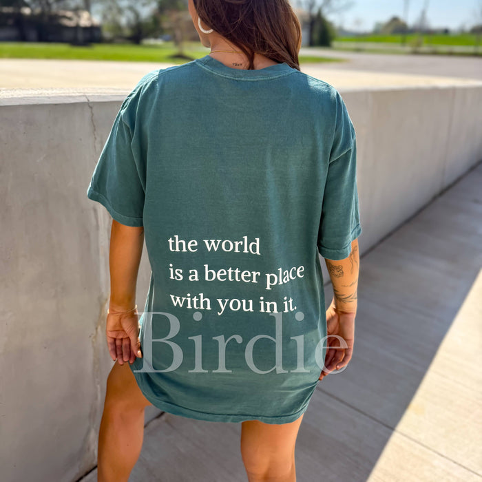 Person wearing a teal t-shirt with a message and 'Birdie' branding, standing outdoors.