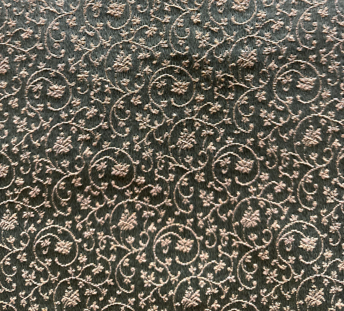A close-up image of a patterned fabric with a floral design in a bronze color.